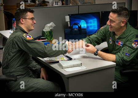 Lt. Col. Alexander Heyman, Commander, 71st studente squadrone e 2° Lt. Mitchel Bie Vance studente pilota, agitare le mani dopo il cambio del dollaro a seguito del Bie 'Dollaro Ride' 8 marzo, 2018, Vance Air Force Base, Okla. È tradizione che gli studenti nei corsi di laurea specialistica di formazione pilota per dare loro istruttore un dollaro dopo il loro primo volo. (U.S. Air Force foto di Airman Zachary guarire) Foto Stock