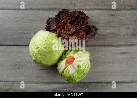 Vista dall'alto su insalata iceberg e lollo rosso (rosso corallo lattuga) grigio sulla scrivania di legno. Foto Stock