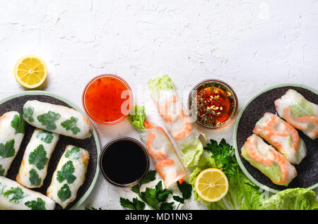 Fresh vietnamita, asiatici, cibo cinese sul telaio di cemento bianco sullo sfondo. Involtini primavera carta di riso, lattuga, insalata, vermicelli, tagliatelle, gamberi, pesce Foto Stock