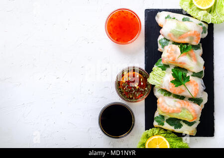 Fresh vietnamita, asiatici, cibo cinese sul telaio di cemento bianco sullo sfondo. Involtini primavera carta di riso, lattuga, insalata, vermicelli, tagliatelle, gamberi, pesce Foto Stock
