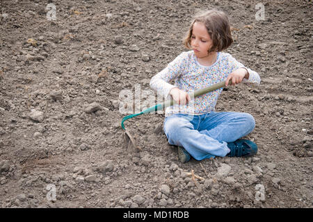 La ragazza lo scavo a secco di suolo organico da hoe. Foto Stock