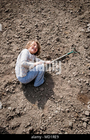 Ragazza posa sul terreno con la zappa in mano avente tempo divertente. Foto Stock