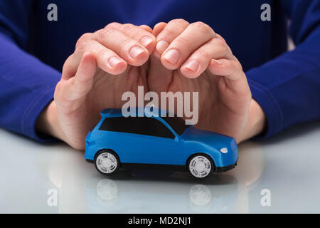 Close-up di mano di una persona tutelare le piccole auto blu Foto Stock