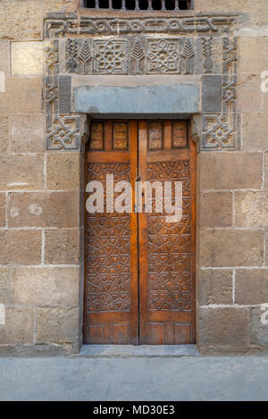 In legno porta ornati geometrici con motivi incisi su vecchi esterna decorata mattoni muro di pietra che conduce a Beit (casa) Al Sehemy casa storica, Foto Stock