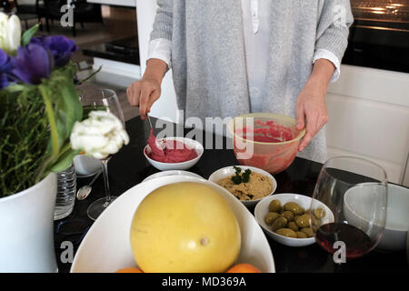 La donna la preparazione di barbabietole hummus e selezione di piatti vegetariani platers-insalata mista,verde verde oliva,hummus classico. Foto Stock