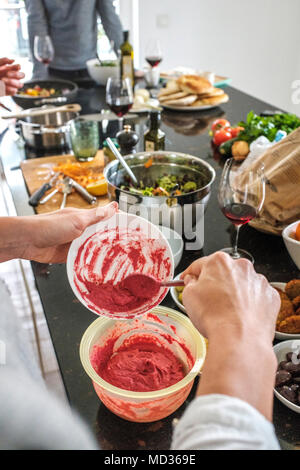 La donna la preparazione di barbabietole hummus e selezione di piatti vegetariani platers-insalata mista,verde verde oliva,hummus classic.Gruppo di amici snacking casualmente su un sel Foto Stock