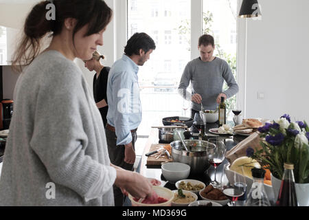 Gruppo di amici snacking casualmente su una selezione di prodotti alimentari ridendo e divertendosi. Foto Stock