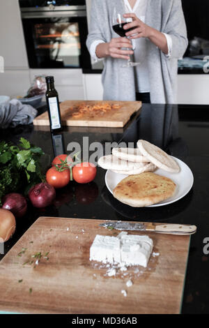 Pane piatto ,e la fetta di formaggio.donna con un bicchiere di vino rosso durante la preparazione di un sano pasto vegetariano-messa a fuoco selettiva Foto Stock