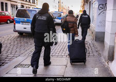 18 aprile 2018, Germania, Dresda: poliziotti scortare una donna per il suo modo per la verifica delle identità durante un raid. A livello nazionale si è supposto che ciò la misura più grande raid della polizia. La polizia ha anche gestito in Sassonia, Sassonia-Anhalt e Turingia targeting la prostituzione e il traffico di esseri umani. Foto: Tino Plunert/dpa-Zentralbild/dpa Foto Stock