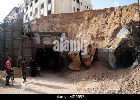 Damasco, Siria. Xviii Apr, 2018. Persone stand all'ingresso di un tunnel sotterraneo nel quartiere Douma, a est di Damasco, Siria, il 18 aprile 2018. Dopo i ribelli' evacuazione dalla Douma prima di questo mese l'intero Ghouta orientale campagna a est di Damasco ha restituito a sotto il controllo del governo. Credito: Ammar Safarjalani/Xinhua/Alamy Live News Foto Stock