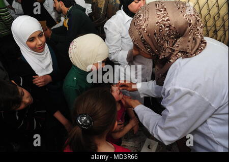 Damasco, Siria. Xviii Apr, 2018. Un infermiere fornisce vaccini per i bambini nel quartiere Douma, a est di Damasco, Siria, il 18 aprile 2018. Dopo i ribelli' evacuazione dalla Douma prima di questo mese l'intero Ghouta orientale campagna a est di Damasco ha restituito a sotto il controllo del governo. Credito: Ammar Safarjalani/Xinhua/Alamy Live News Foto Stock