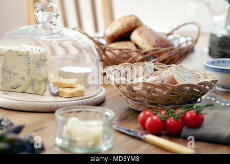 Tavolo con pane fresco, formaggi e pomodori a grappolo Foto Stock
