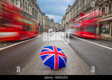 Londra, Inghilterra - British ombrello occupato a Regent Street con iconico autobus rossi a due piani in movimento Foto Stock