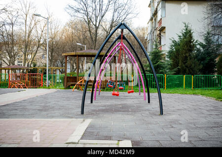 Altalena per bambini nel mezzo di un parco giochi per bambini Foto Stock