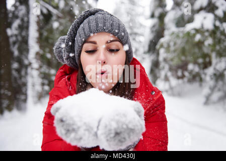 Giovane donna fiocchi di neve di soffiatura off mani Foto Stock