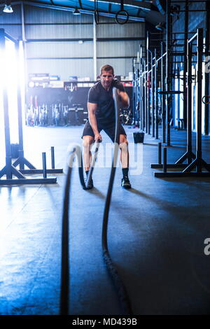 L'uomo esercizio in palestra, utilizzando corde di battaglia Foto Stock