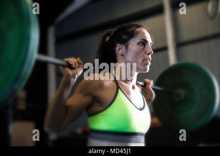 Donna esercizio in palestra, utilizzando barbell Foto Stock