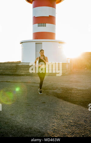 Giovani femmine runner in esecuzione sulla costiera traccia di sporco al tramonto Foto Stock
