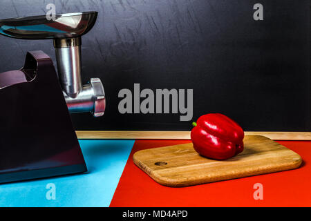 Cucina ancora la vita di elettrico tritacarne e paprica in un colorato tabella Foto Stock