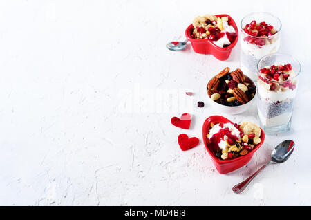 Colazione romantica con chia, muesli, yogurt e frutti di bosco sul vecchio cemento bianco sullo sfondo. La salute e la dieta concetto Foto Stock