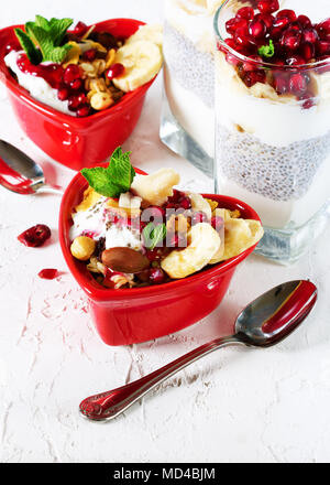 Colazione romantica con chia, muesli, yogurt e frutti di bosco sul vecchio cemento bianco sullo sfondo. La salute e la dieta concetto Foto Stock