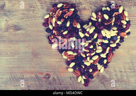 Mix di frutta secca forma di cuore raccolta su sfondo di legno. Tonica Foto Stock