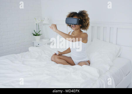 Donna di contenuto in occhiali VR sul letto Foto Stock