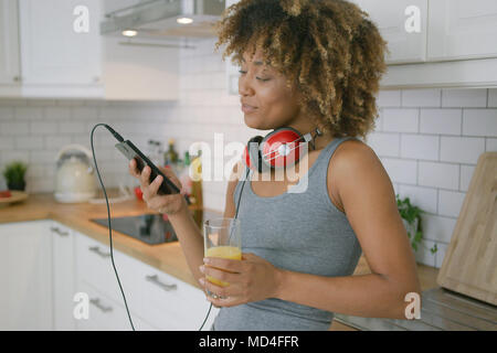 Donna informale rilassante con il telefono in cucina Foto Stock