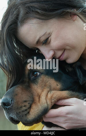 Una chiusura di una donna che abbraccia il suo cane. Foto Stock