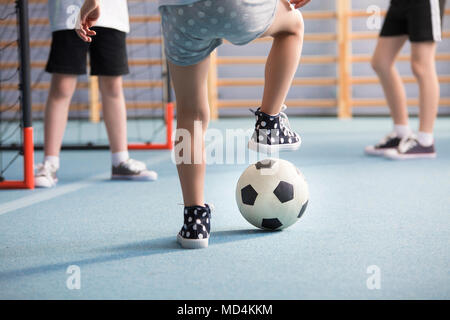 Close-up di ragazzi alle gambe indossando sneakers mentre giocano a calcio nel parco giochi Foto Stock