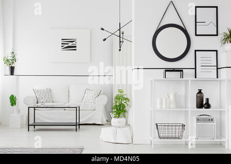 In bianco e nero salotto interno con divano, tavolo, scaffali, ornamenti, poster e piante Foto Stock