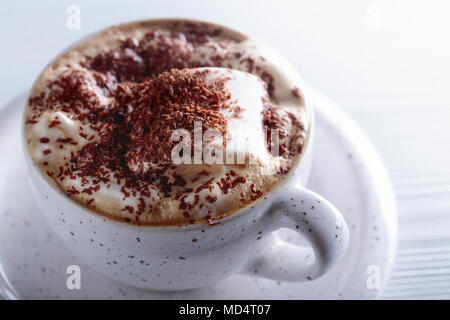 Cioccolata calda e marshmallow cosparso con scaglie di cioccolato bianco su un tavolo di legno. Foto Stock