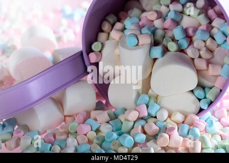 Violetta secchio con vari marshmallows su uno sfondo di colore rosa. Foto Stock