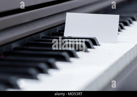 Un fustellato business card collocato tra la tastiera di pianoforte racing Foto Stock