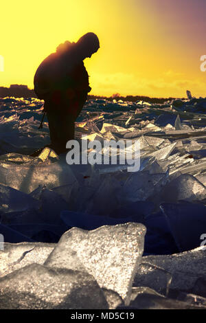 Camminare in inverno lungo il mare. Caldo sole del tramonto e sagome di un uomo Foto Stock