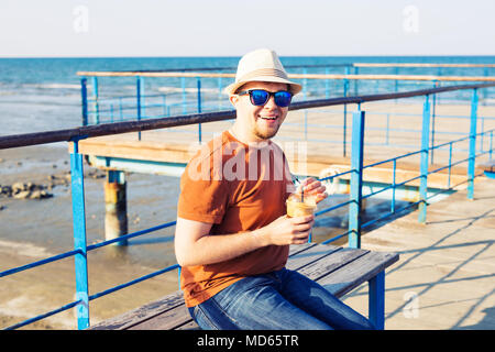 Lo stile di vita, le bevande e il concetto di persone - uomo in occhiali da sole di bere il caffè Frappé di carta usa e getta cup all'aperto Foto Stock