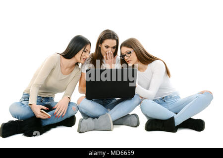 Le tre ragazze seduto a terra, cross gambe, tenendo laptop Foto Stock