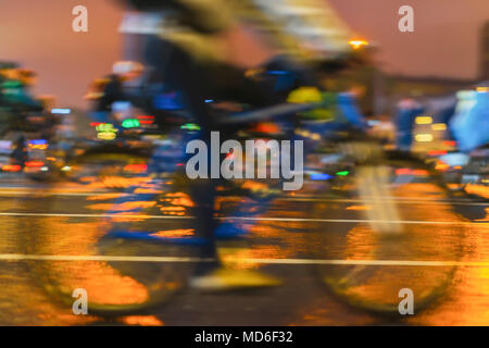 Biker sulla bicicletta, il ciclista con il piede sui pedali di close-up. Sfilata di ciclisti in città, luce notturna, bokeh di fondo. Sport e stile di vita sano concetto. Abstract sfondo sfocato Foto Stock