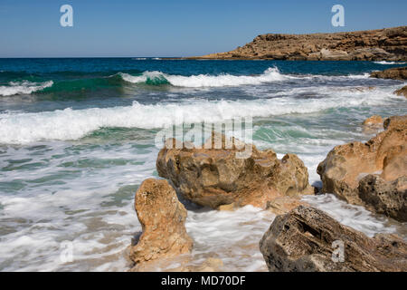 Giornata di sole a Creta, colorato onde del mare presso la costa rocciosa nella parte orientale dell'isola. Offuscata dal moto dell'acqua. Foto Stock