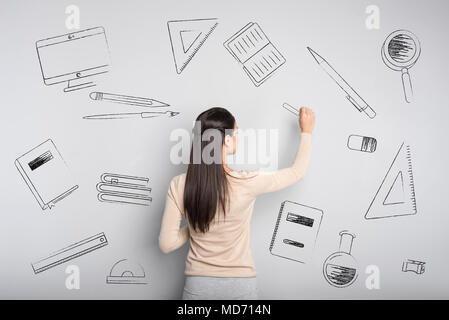 Calma insegnante cercando concentrati durante la scrittura sulla lavagna Foto Stock