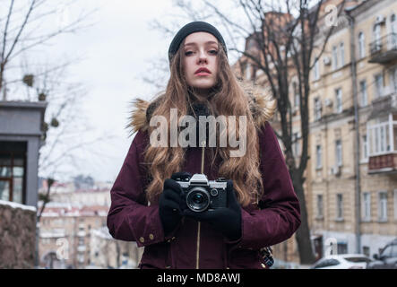 Hipster ragazza fotografo con retro fotocamera per scattare delle foto a camminare su una strada di città Foto Stock