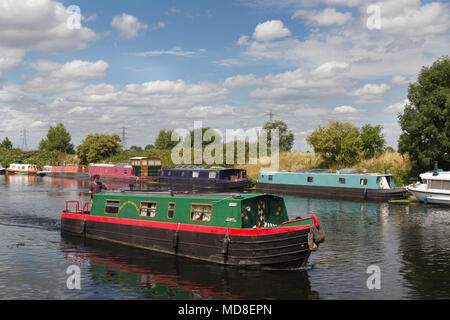 Un giovane uomo di manzi un colorato narrowboat lungo il fiume Lea nel nord di Londra su una soleggiata giornata estiva Foto Stock