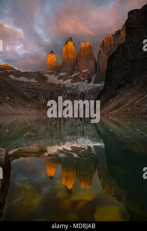 Le torri della Cordillera Paine nel Parco Nazionale Torres del Paine all alba con i colori nelle nuvole e sulle torri con evidenti riflessi sul lago Foto Stock