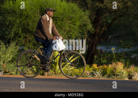 Un ciclista cavalca un roadster tradizionale stile di bicicletta, comunemente chiamato "Black Mamba' in Africa orientale. Anche se sono ancora una visione comune, essi Foto Stock