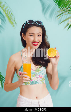 Piuttosto di moda donna asiatica con tazza succo colorato su sfondo blu Foto Stock