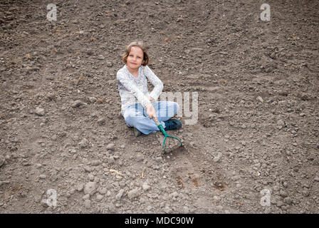 Ragazza scavando nel suolo organico da hoe. Foto Stock