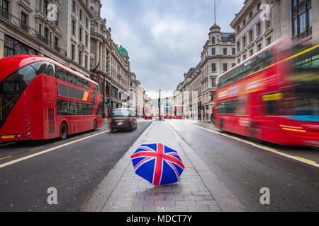 Londra, Inghilterra - British ombrello occupato a Regent Street con iconica red double-decker bus e taxi neri in movimento Foto Stock