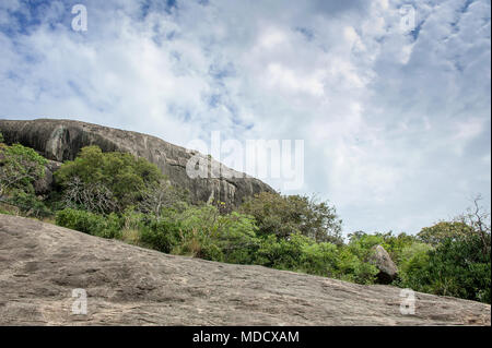 Paesaggio di montagna a Dambulla tempio nella grotta, Sri Lanka. Weathered, rocce di granito, alberi verdi e sfondo con cielo nuvoloso Foto Stock