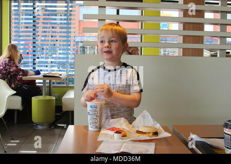 Un piccolo ragazzo avente la colazione al Mc Donald's in Llandudno Foto Stock