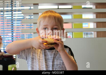 Un piccolo ragazzo avente la colazione al Mc Donald's in Llandudno Foto Stock